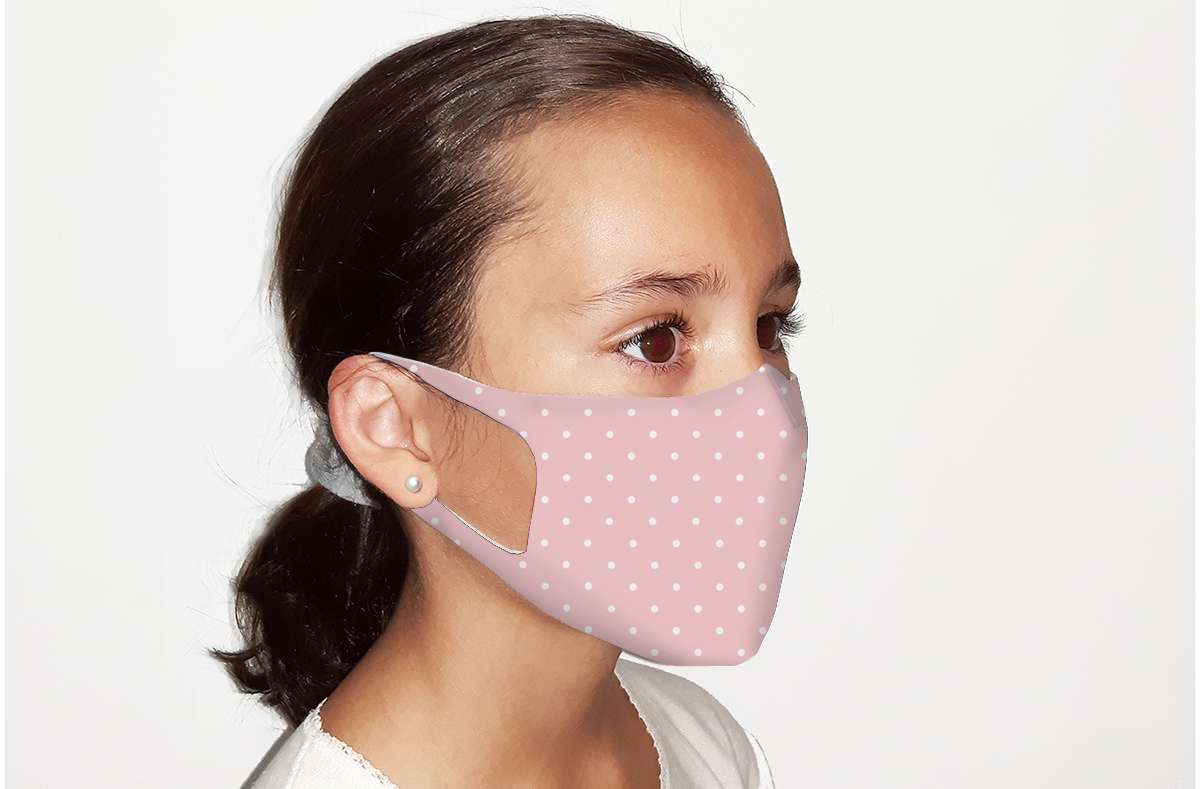 Niña con mascarilla higiénica de tela homólogas color rosa con lunares blancos